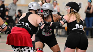 Three Cincinnati Roller Derby blockers getting into formation at CRD's 2025 Halloween bout